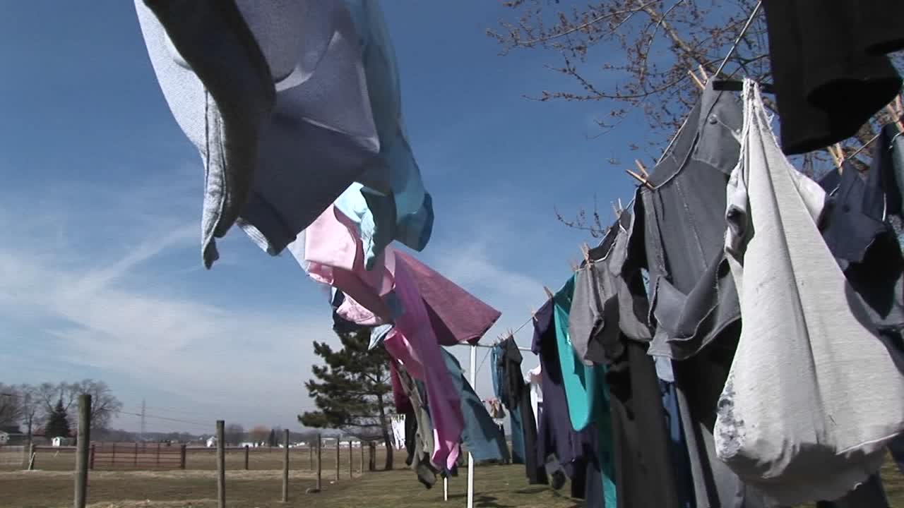 카메라는 시골 지역 사회에서 건조하기 위해 야외에 걸려있는 옷을 통해 패닝합니다.