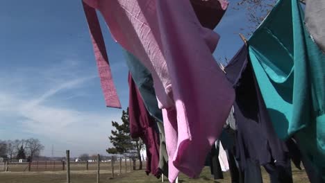 the camera pans through clothes hanging outdoors to dry in a rural community