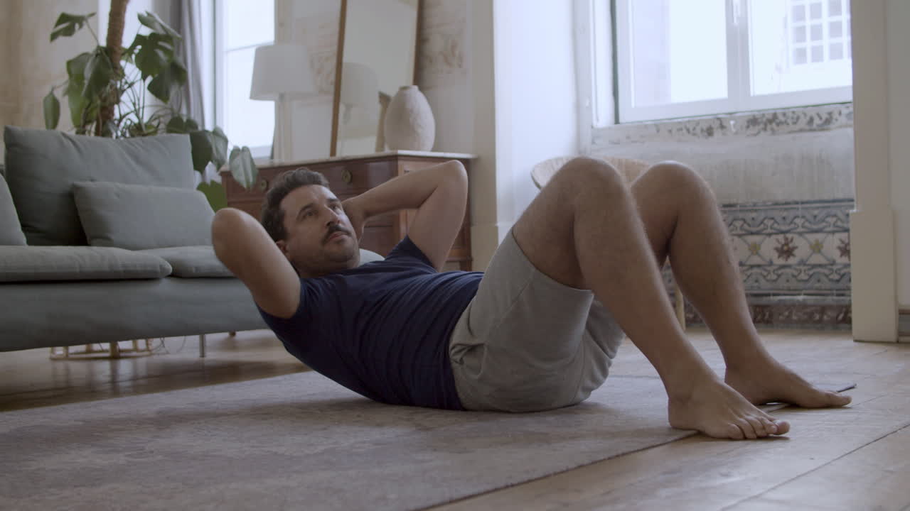 hombre enfocado acostado en el suelo y haciendo ejercicios abdominales