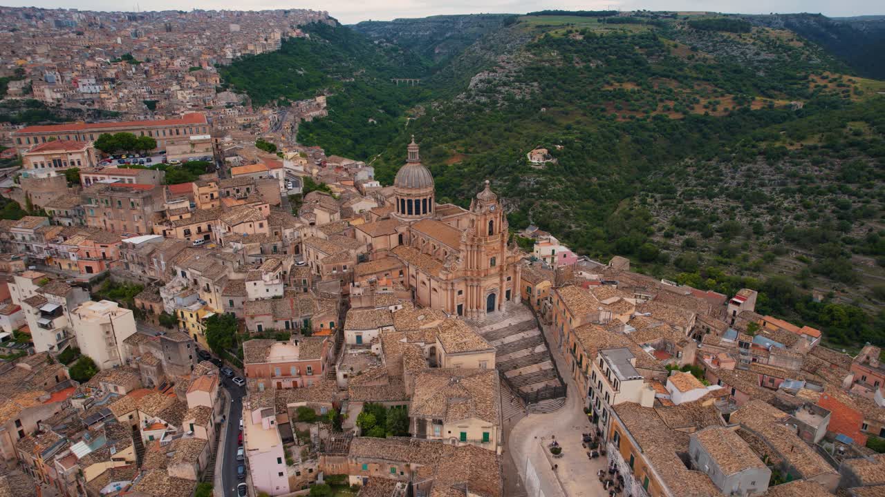 Top-down aerial view of Ragusa Ibla rooftops and curved roads in cinematic daylight. Sicily, Italy.