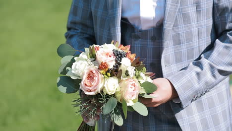 groom holding wedding bouquet. young man with flowers.