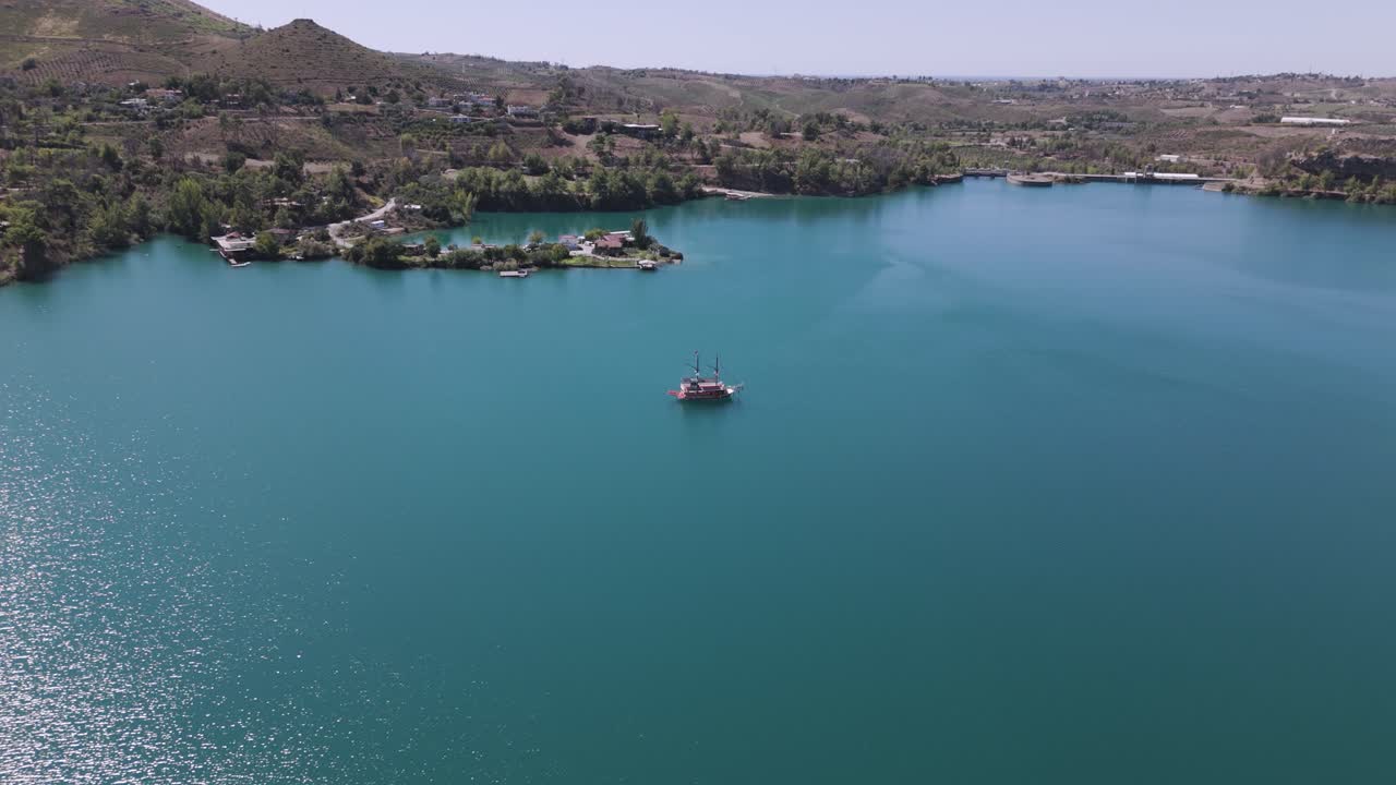 Lone boat anchored in middle of stunning Green lake, Taurus mountains Turkey, aerial descend