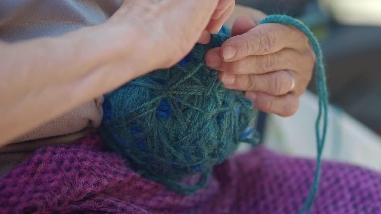 Close-up of hands knitting with blue yarn