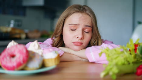 mujer joven eligiendo entre verduras y dulces. chica triste buscando