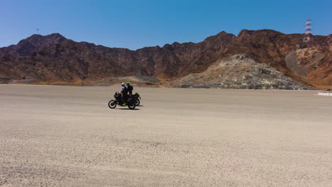adventure bikes ride on a flat off-road dirt track on a sunny summer day. drone shot.
