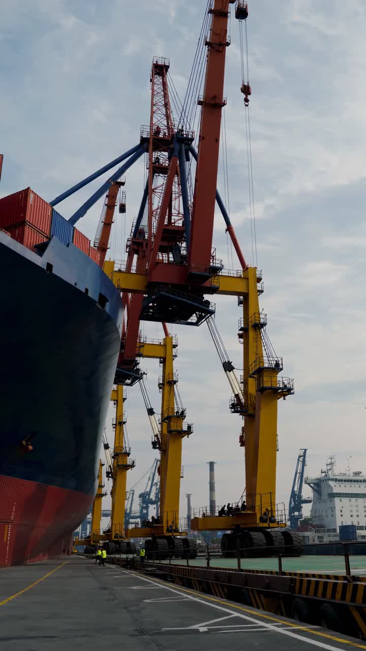 Low-angle video shot of towering cranes at a busy port, capturing the industrial scale and dynamic