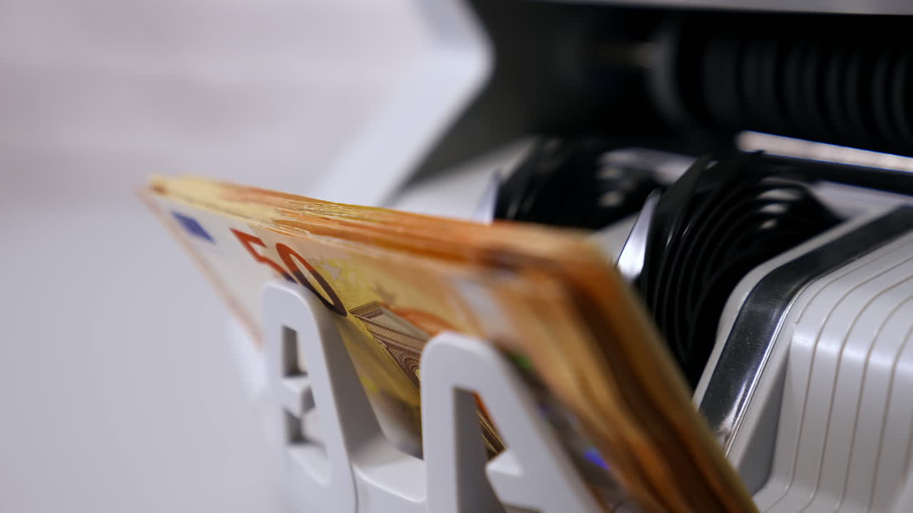 Modern banking activity. Euro banknotes while being counted. Hand of a cashier taking money from counter machine. Close-up.