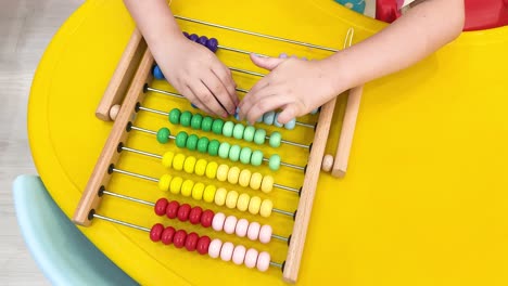 child learning math with colorful wooden abacus