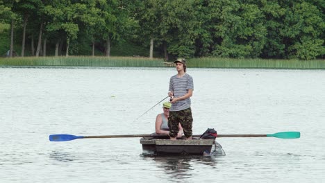 old angler with a grandson sitting in the boat on the lake with a rod while fishing. outside.