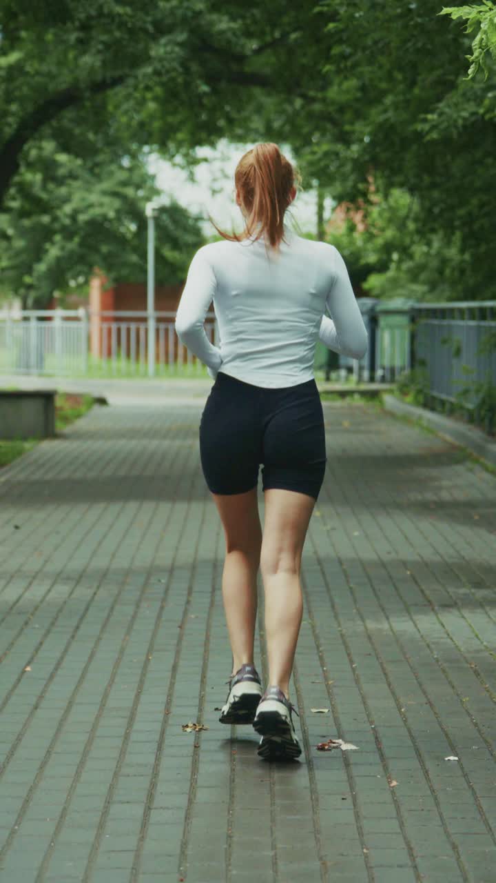 A Woman Jogging Along a Tree-Lined Pathway, Embracing a Healthy Lifestyle and Enjoying an Active Outdoor Exercise Routine