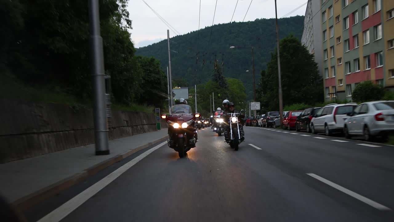 Rolling tracking shot in front of a group of motorbikes driving down city street