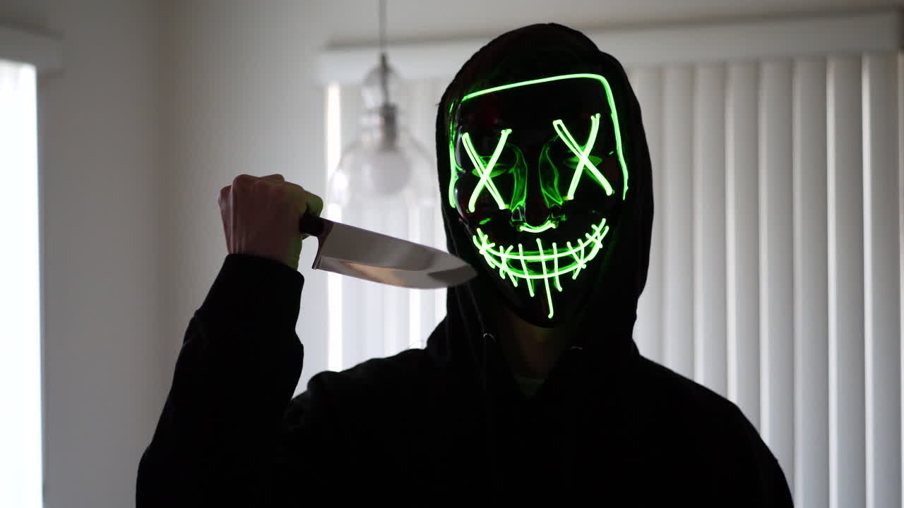 un asesino en serie slasher aterrador con una máscara de halloween de terror tirando un cuchillo a su víctima de asesinato