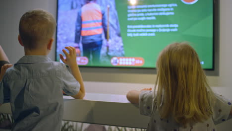 two little children looking at a screen in a natural history museum, rear view