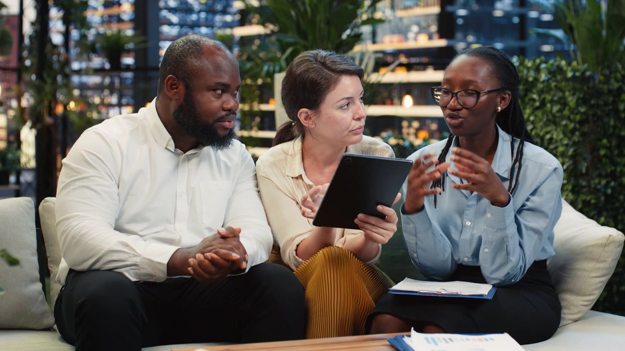 Businessman points to tablet screen during rooftop lounge workspace presentation