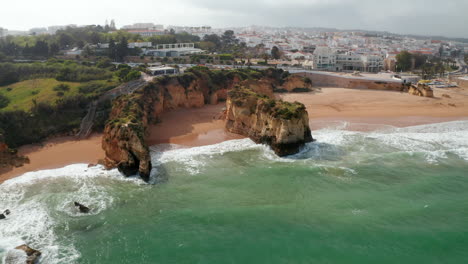 Sensational-aerial-drone-view-of-paradisiac-Lagos-coast-beach-landscape-in-Algarve,-Portugal,--flying-above-ocean-reveal-townscape,-sunny-day