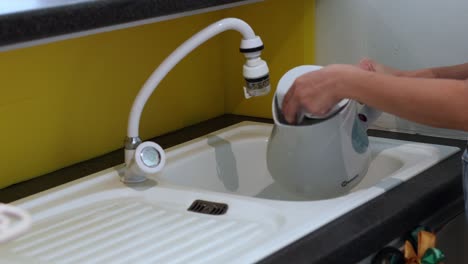 person fills kettle with water, then places on base