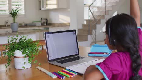 Niña-Hispana-Sentada-En-La-Mesa-Usando-Una-Computadora-Portátil-Con-Auriculares