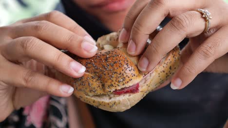 una mujer comiendo un sándwich de bagel.
