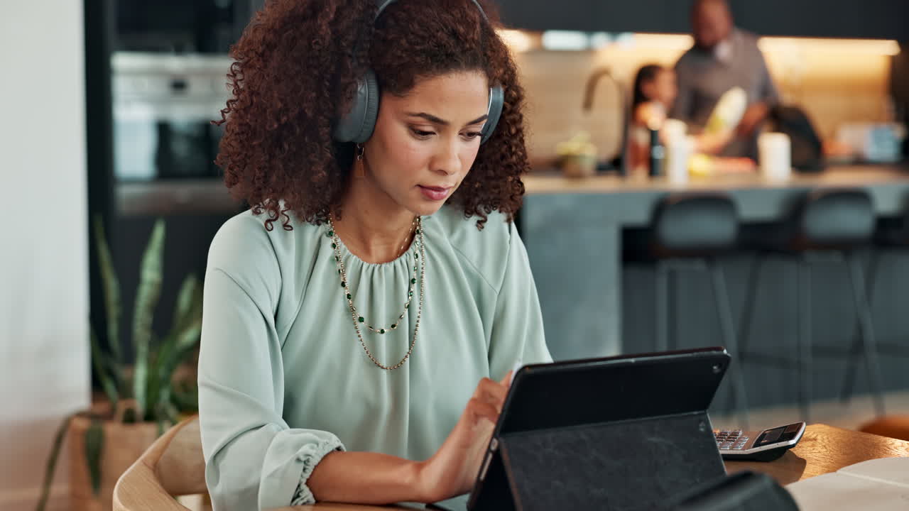 Woman working on tablet at home with family in background