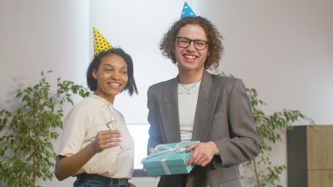 retrato de wo felices colegas multiétnicos con gorro de fiesta mirando a la cámara durante una fiesta en la oficina