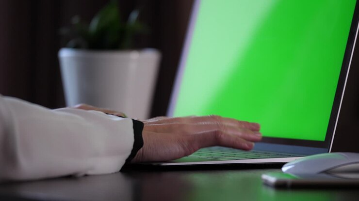 Hände in weißem Hemd tippen auf der Tastatur eines Laptops und bewegen eine Maus.