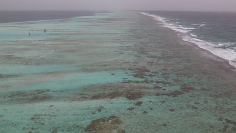 aerial time hyper lapse over fringing reef as kite surfers coast in ocean water of los roques