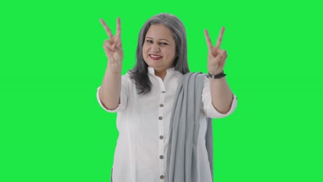 feliz mujer de negocios india senior mostrando el signo de la victoria pantalla verde