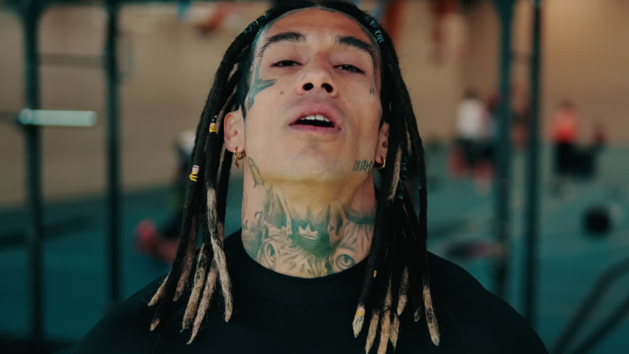 Uomo con dreadlock e tatuaggi in palestra