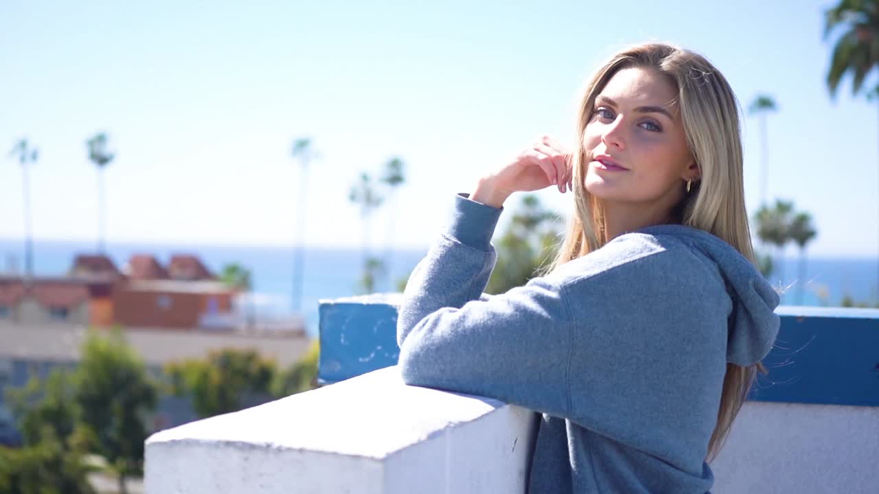 Una joven rubia con sudadera deportiva con capucha cerca de la playa