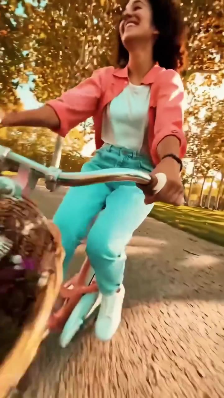 Giovane donna che pedala gioiosamente in bicicletta con fiori in un parco soleggiato