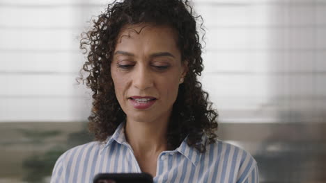 portrait-of-beautiful-hispanic-business-woman-texting-browsing-using-smartphone-checking-messages-corporate-networking-in-office-background