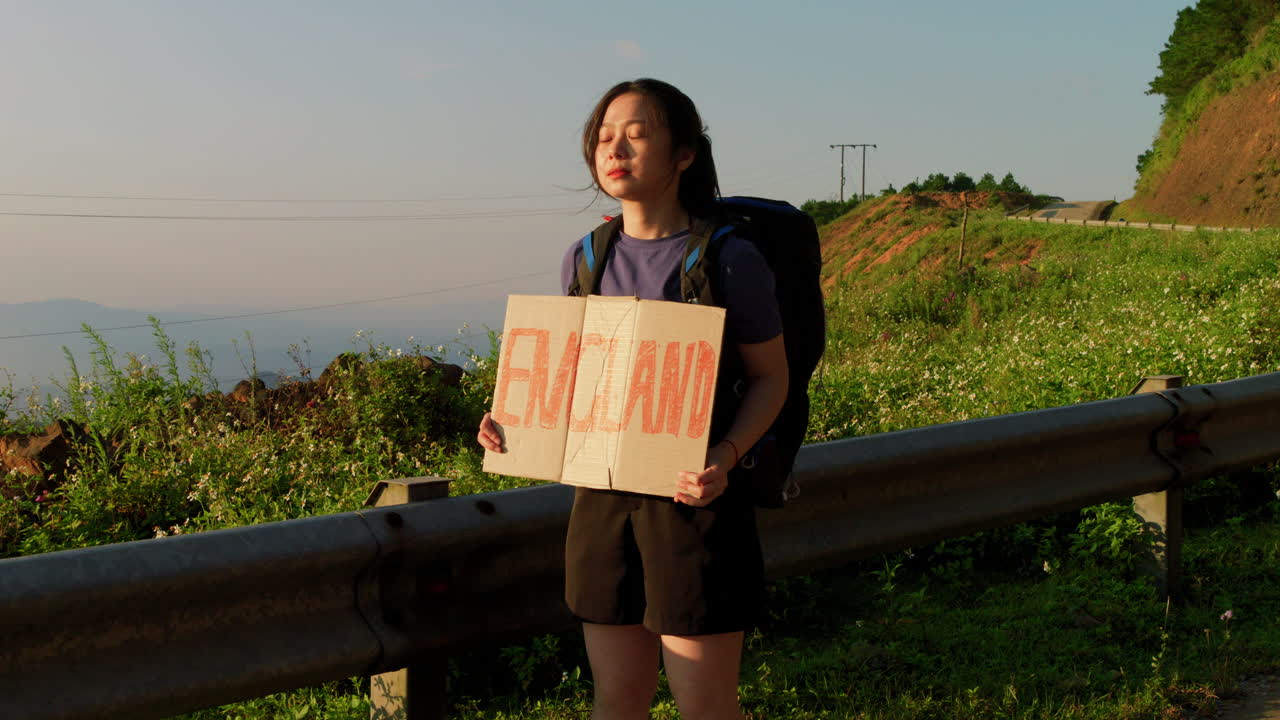 영국 여행 목적지 슬로우 모션 로드 트립이라는 카드보드에 표지판을 붙인 젊은 여성 솔로 여행자 배 ⁇  여행자