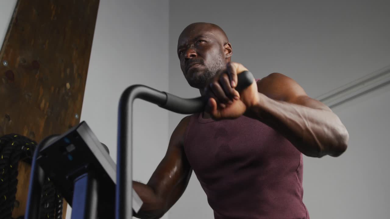 Fit african american man exercising on training bike inside gym