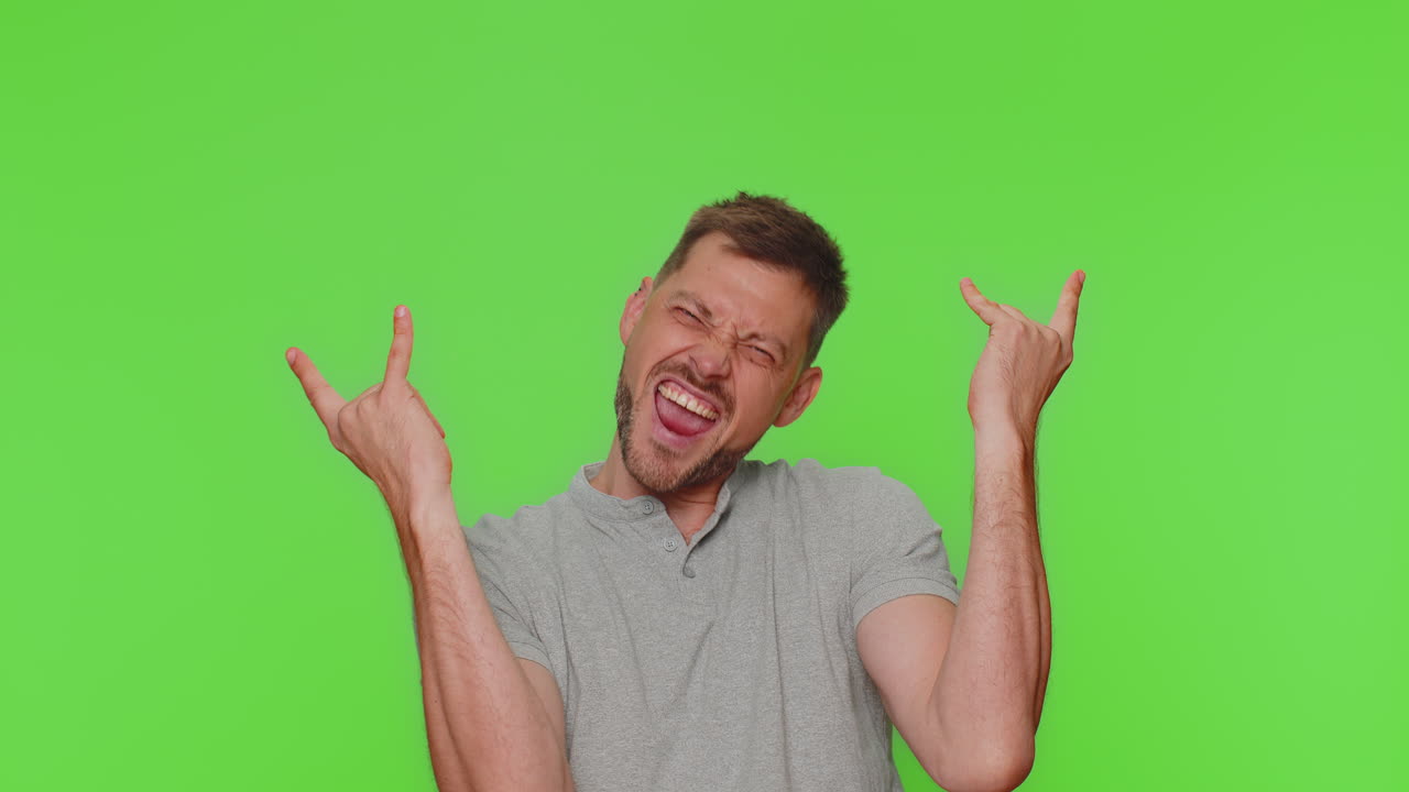 Overjoyed delighted handsome man showing rock n roll gesture, dancing ...