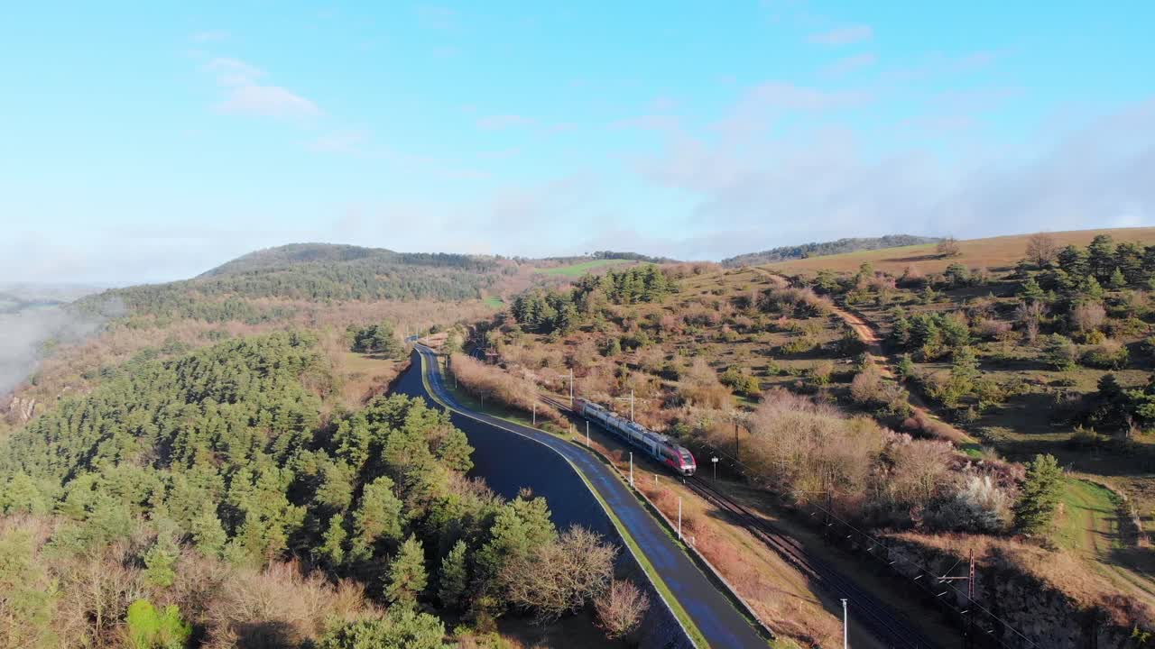 Train Traveling Through a Scenic Forested Landscape with a Winding Road