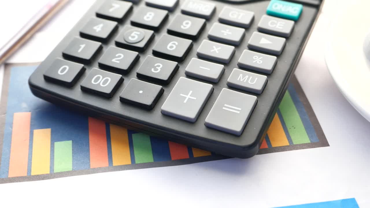 Close-up de uma calculadora e gráficos financeiros em uma mesa