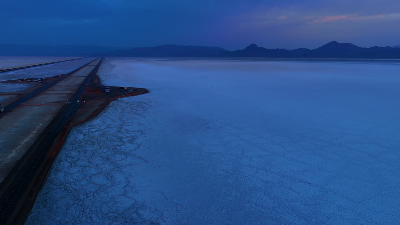 Crusty salty landscape crossed by the roads. Drone footage over the Bonneville Salt Flats, Utah, United States at dusk time