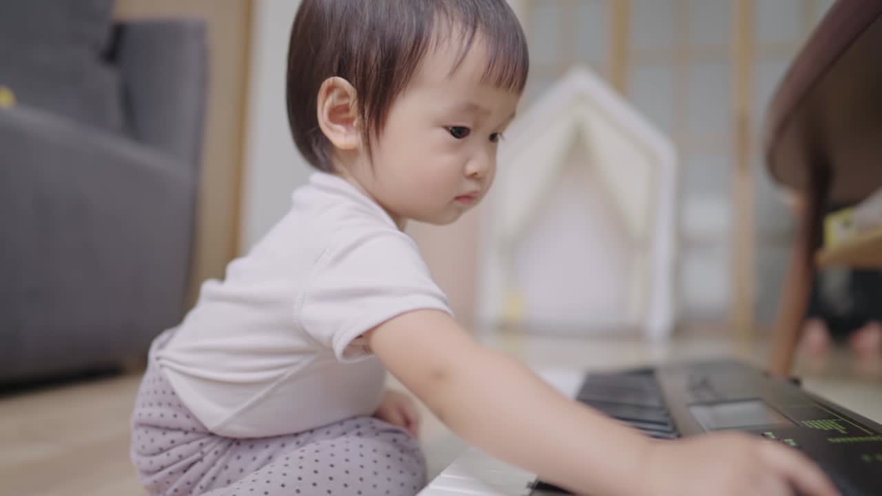 A curious baby girl using finger presses on electronic piano keyboard on living room floor, learning by playing, rising child and giving education, kids in play time, innocence and curiosity in kids