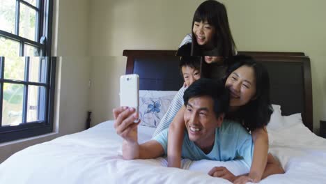 Happy-family-taking-a-selfie-on-mobile-phone-in-the-bed-room-4k