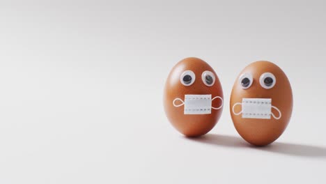 video of eggs with eyes and face masks on a white surface