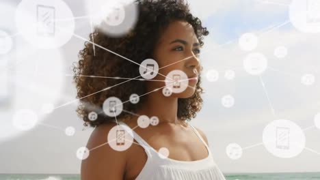 red de iconos digitales contra mujer afroamericana de pie en la playa