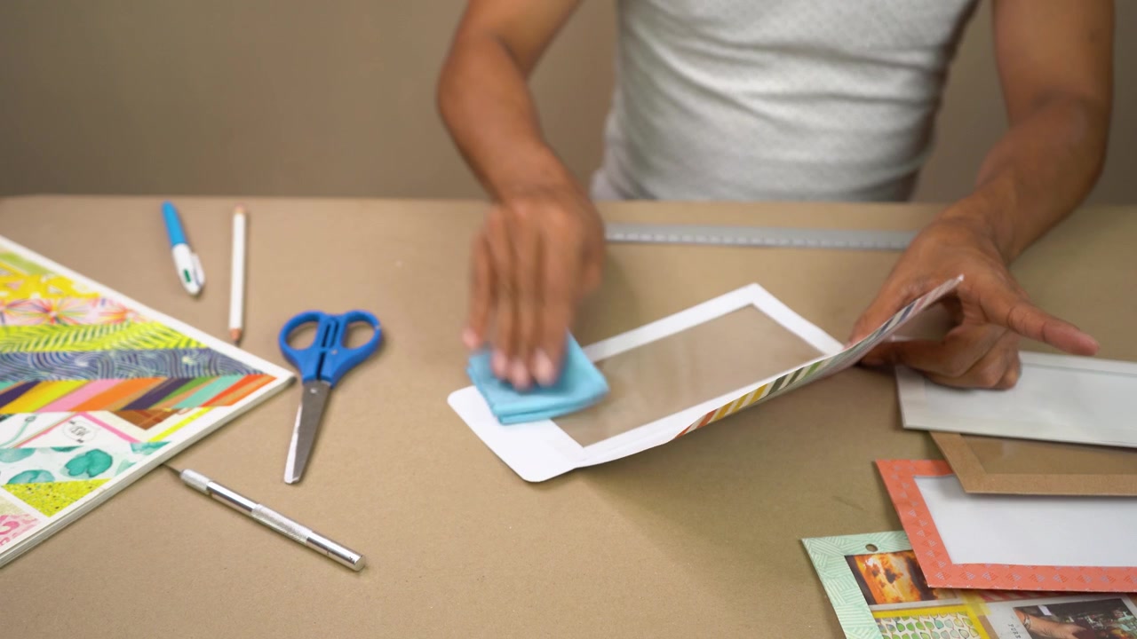 Hands assembling and decorating paper crafts with tools on tabletop workspace