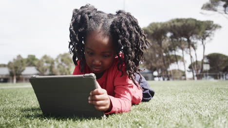young girl using tablet on grass in park, enjoying outdoor learning