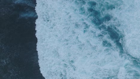 Top-Down-Slow-Motion-Drone-of-wave-action-at-low-tide-over-coral-and-rock-reef-Nyang-Nyang-Beach,-Bali,-Uluwatu-Indonesia