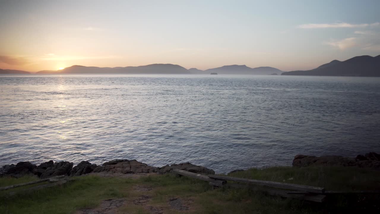 Majestic sea hilly landscape with sun setting down behind, panning right view