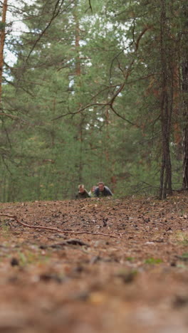 teenagers group in clothes of middle age period runs along road in fir forest slow motion. boys and girls at historical camp. children development