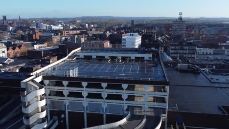 Overhead-aerial-view-above-city-multi-storey-car-park-quiet-British-urban-public-streets-at-sunrise-pull-away-pan-left