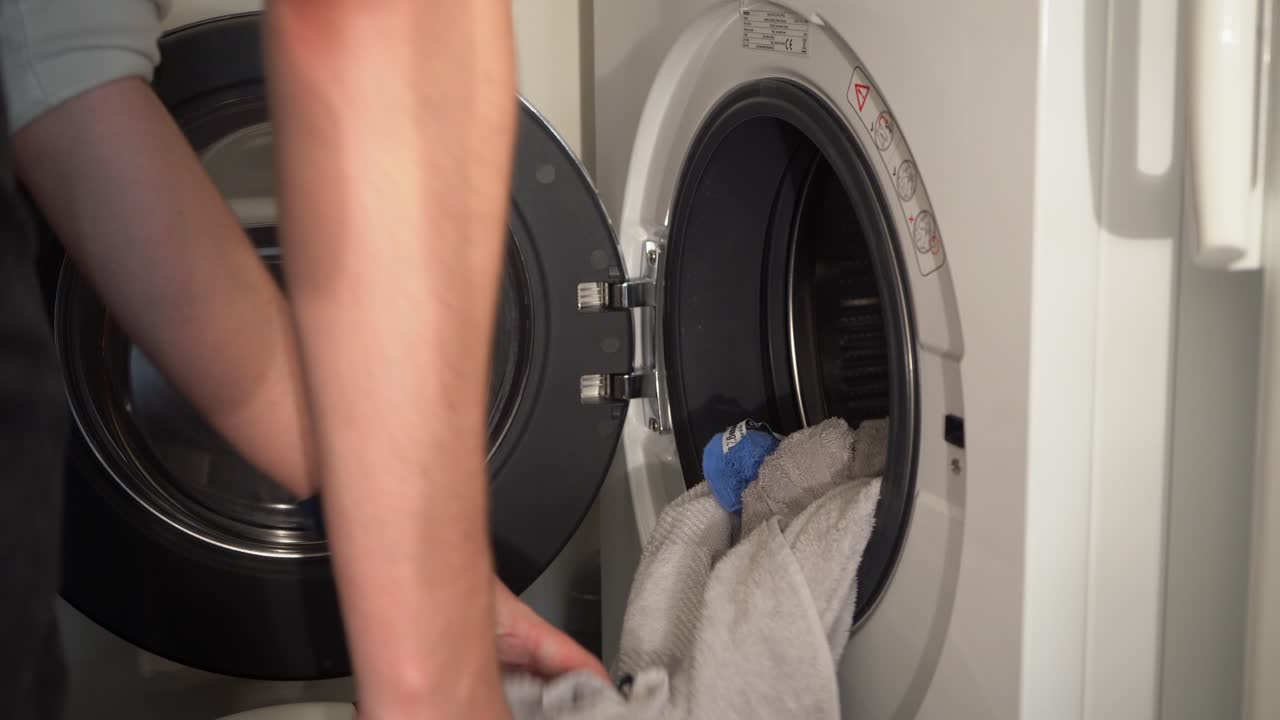 primer plano: el joven vacía la lavadora en el cesto de la ropa