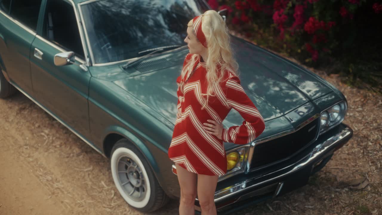 Stylische Frau im Retro-Kleid posiert neben Oldtimer