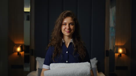 una doncella de hotel sonriente sosteniendo toallas.